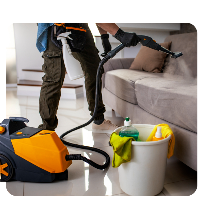 عامل يستخدم جهاز بخار احترافي لتنظيف وتعقيم الكنب داخل المنزل