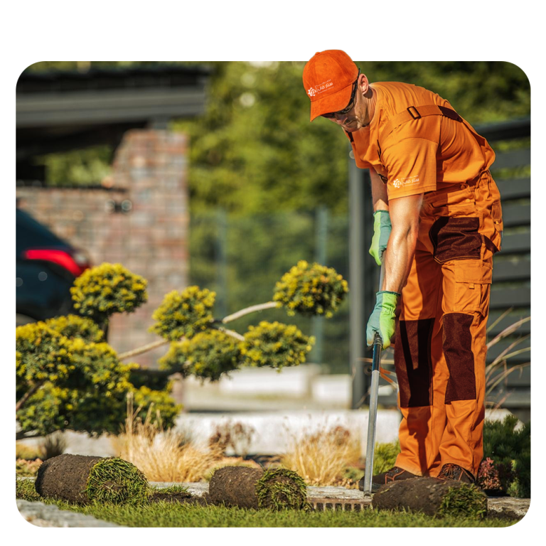 عامل من مجموعة ستار يقوم بتنسيق الحديقة وزراعة العشب الطبيعي أمام المنزل